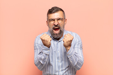 adult handsome man shouting aggressively with annoyed, frustrated, angry look and tight fists, feeli