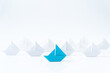 Leadership or leader concept using a blue paper ship leading among white ships