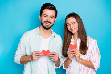 Sticker - Photo of pretty charming young couple wear casual shirt holding red paper hearts isolated blue color background