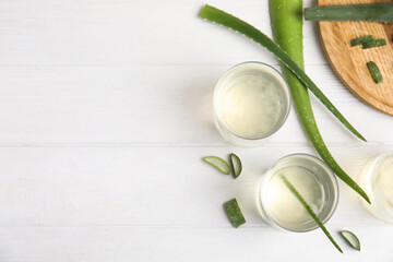 Flat lay composition with fresh aloe drink and leaves on white wooden table. Space for text