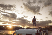 Man Enjoying The Sunset On The Roof Of His Camper Van