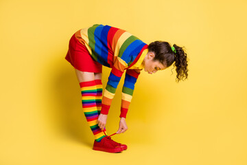 Sticker - Full size profile side of girl tying shoe laces sneakers isolated over yellow color background