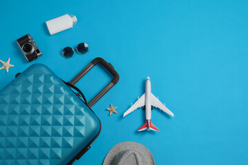 Canvas Print - Flat lay composition with suitcase and travel accessories on light blue background. Summer vacation