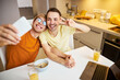 © Svitlana - Cheerful happy gay couple making selfie at home