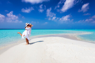 Happy couple in love is having fun and hugging on a sandbar with white sand and turquoise ocean