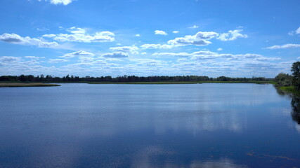 Naklejka na meble Clouds are reflected in the lake. View of the lake in the distant grass and clouds