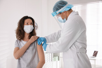 Wall Mural - Doctor vaccinating mature woman against Covid-19 in clinic