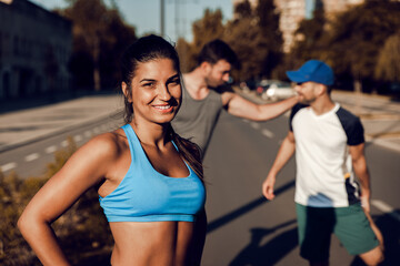 Sticker - Group of sports people stretching muscles before running in city street in morning.