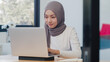 © tirachard - Beautiful Asia muslim lady casual wear working using laptop in modern new normal office. Working from home, remotely work, self isolation, social distancing, quarantine for coronavirus prevention.