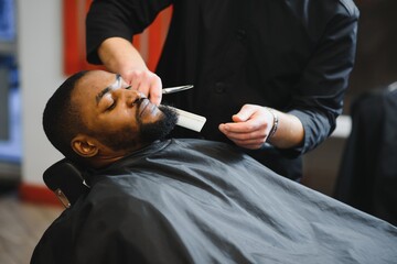 Black man in the barbershop. Cute black man makes a haircut in the African salon. Hair style. Haircut for adults.