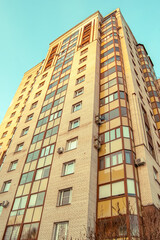 An apartment building on the background of clear sky, view from below.