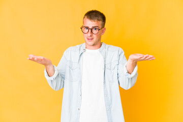 Young caucasian handsome man makes scale with arms, feels happy and confident.