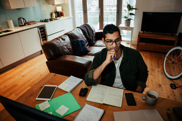 Wall Mural - Mixed race businessman concerntrating while reading off desktop computer and writing in note pad