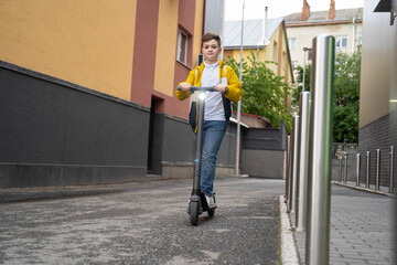 Wall Mural - Handsome teenager rides on electric scooter down the city street