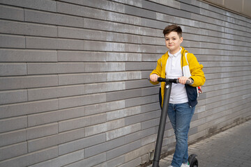 Wall Mural - Handsome teenager rides on electric scooter down the city street