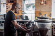© Vladimir Borovic - Handsome and urban young tattooed man making coffee on coffee machine in cafe. Young barista is making a coffee.