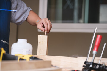 Woodworking operators are using glue to put together the wood parts to assemble and build a wooden table for their customers