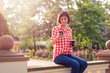 © Vladimir Borovic - Beautiful happy young girl in park on a sunny day drinking coffee to go and using phone