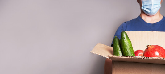 Wall Mural - A courier wearing a mask with box of groceries, safe food delivery