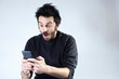 © Moha - White Argentinian adult bearded man using smartphone social media with surprised expression on a white background with copy space.