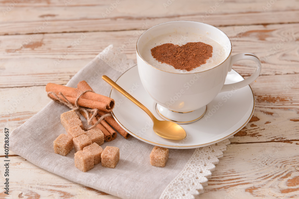 Tasty coffee with cinnamon in cup on wooden background