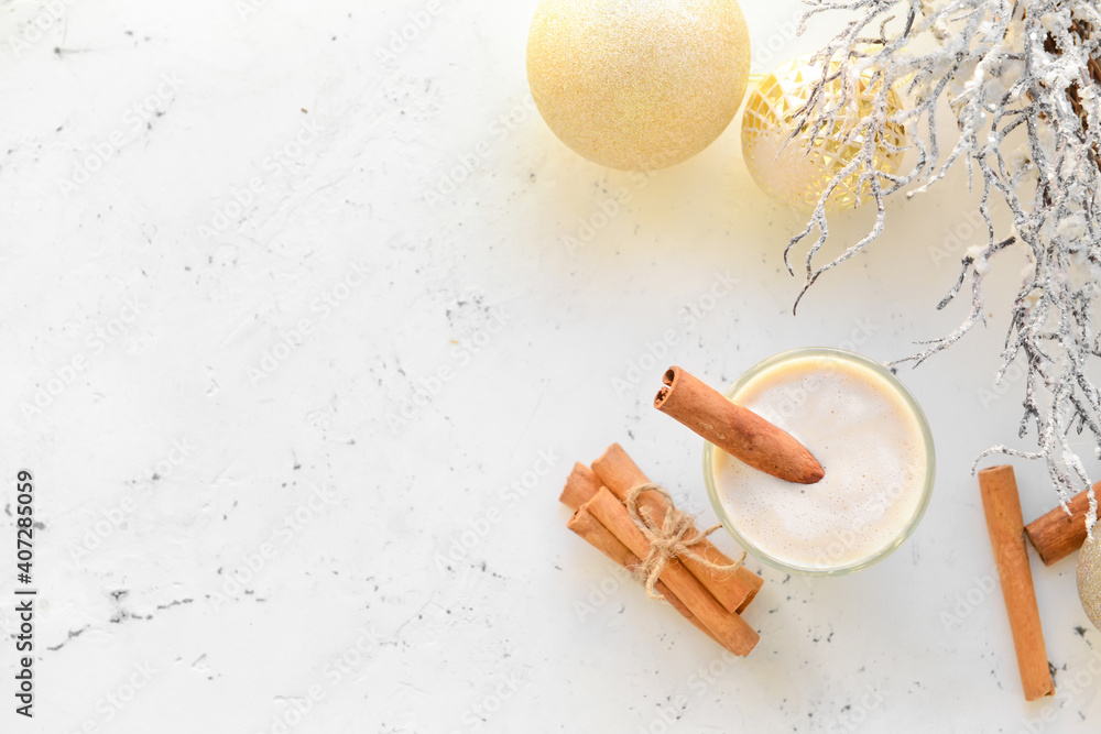 Tasty milkshake with cinnamon in glass on light background