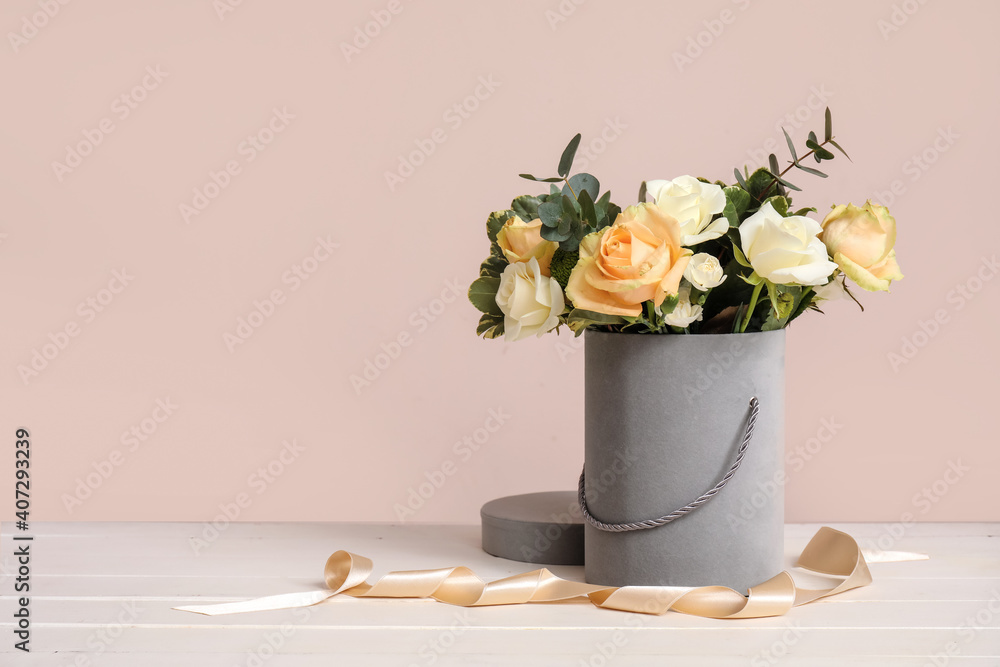 Gift box with beautiful flowers on table against color background
