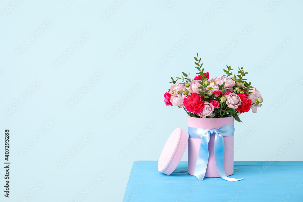 Gift box with beautiful flowers on table against color background