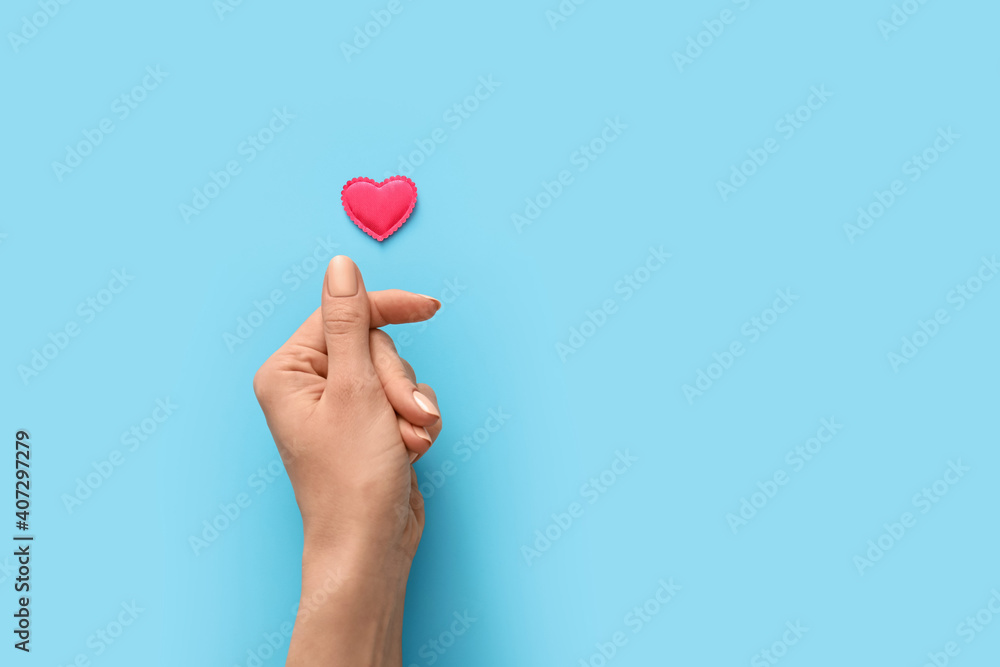 Hand with red heart on color background