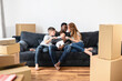 © Vadim Pastuh - Excited mixed race family on relocation day. Overjoyed mother and father with two children sit on the sofa, smiling. Happy parents with son and daughter in new apartment, celebrate moving day