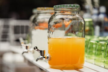 table in the garden with drinks, lemonade, water, cut oranges and glasses