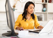 © JackF - Latin American businesswoman sitting in office at workplace and working at laptop