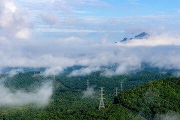 Wall Mural - high voltage power transmission towers in fog on mountain mae moh lampang.