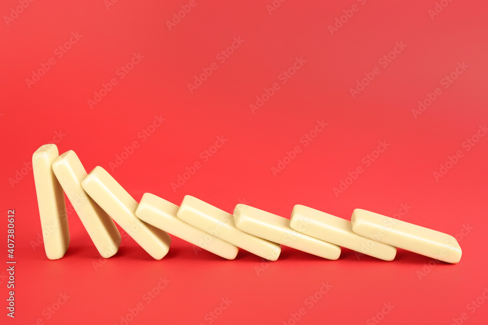 White domino tiles falling on red background. Space for text - obrazy, fototapety, plakaty 
