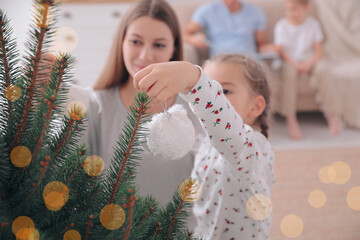 Sticker - Mother with daughter decorating Christmas tree together at home, focus on hand