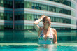 © Maria - young caucasian woman relaxing in a pool on the roof of a skyscraper in a metropolis under the sun