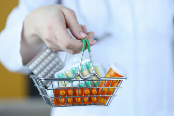 Wall Mural - Doctor holding small grocery basket with medicines closeup