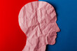 © Marijus - Head silhouette made of paper. Crumpled pink paper shaped as a human head with copy space on red and blue paper background.