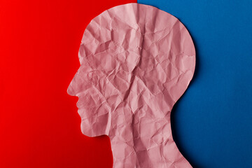 head silhouette made of paper. crumpled pink paper shaped as a human head with copy space on red and