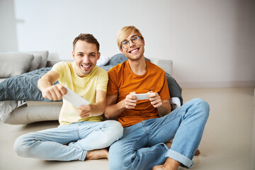 Two joyful young men playing video game at home