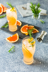 Wall Mural - Two glasses of Paloma cocktails with tequila fresh grapefruit juice combined and rosemary. Gray concrete surface.