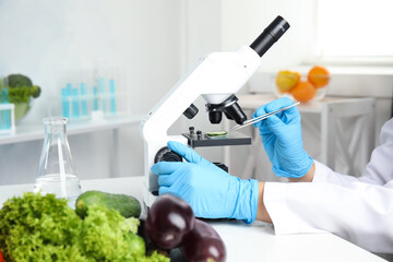 Wall Mural - scientist inspecting slice of cucumber with microscope in laboratory, closeup. poison detection