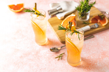 Wall Mural - Two glasses of Paloma cocktails with tequila fresh grapefruit juice combined and rosemary. Light pink concrete surface.