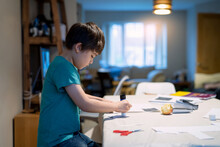 Authentic Portrait Of Preschool Kid Putting Glue Stick On Paper For His School Homework, Young Boy Using Glue Stick On Paper Making DIY Project, Children Learn And Play At Home, Homeschooling