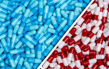 Poster - Top view of blue capsules and red-white capsules pills in a plastic tray. Full frame of two drugs. Pharmacy drugstore products. Pharmacology concept. Healthcare and medicine. Pharmaceutical industry.