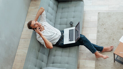 young man is talking on a smartphone in his living room .