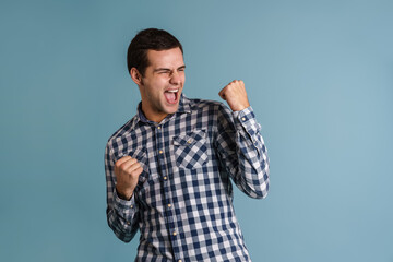 Excited young guy screaming while making winner gesture