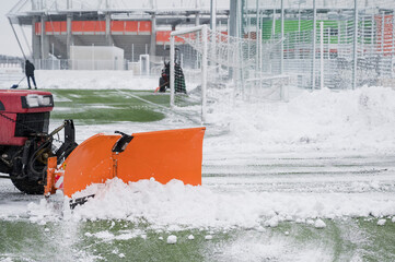 Removing snow with tractor from the soccer pitch.