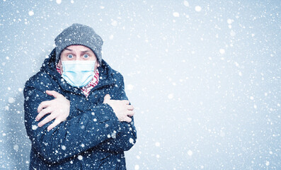 Frozen man in winter clothes on his face wearing a respirator mask to protect against the virus covid, snow around