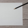 © Aleks Kend - Close-up of pencil on clean white paper blank. Wooden table background. Top view.